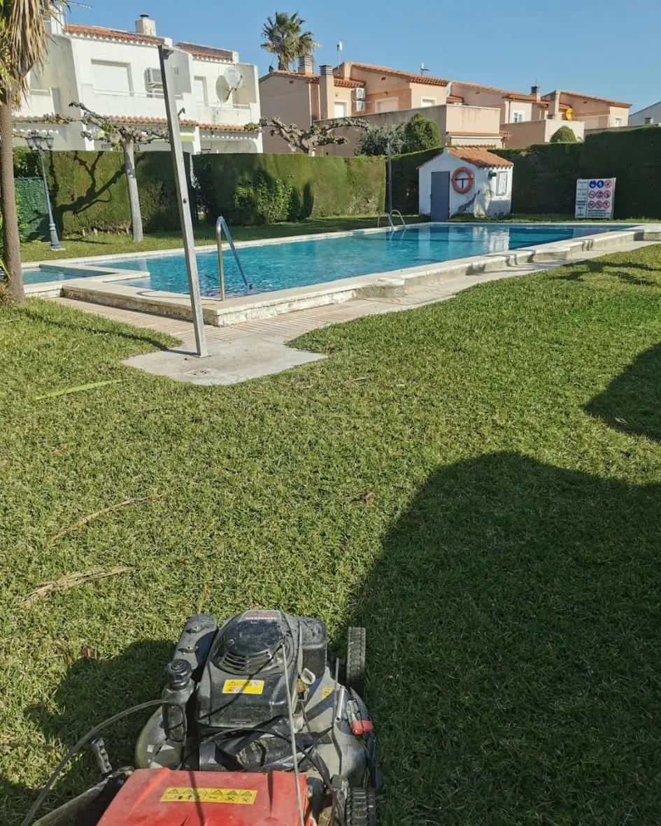 Cortacésped sobre el césped recién segado de una piscina comunitaria