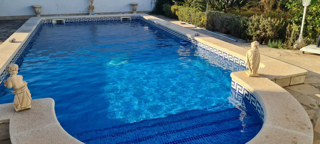 Piscina de gresite azul con escalones de obra y chorros de agua en el borde